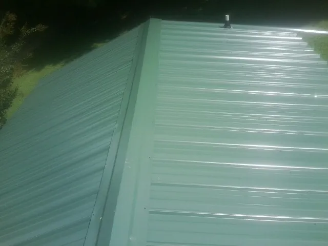 New green metal panels meeting at the ridge of a roof — Flat Roof Repair work by our crew in Brasstown