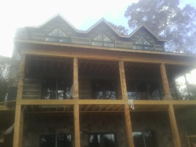 Dormers and porch framing on a large log home under construction — Roof Coating work by our crew in Brasstown