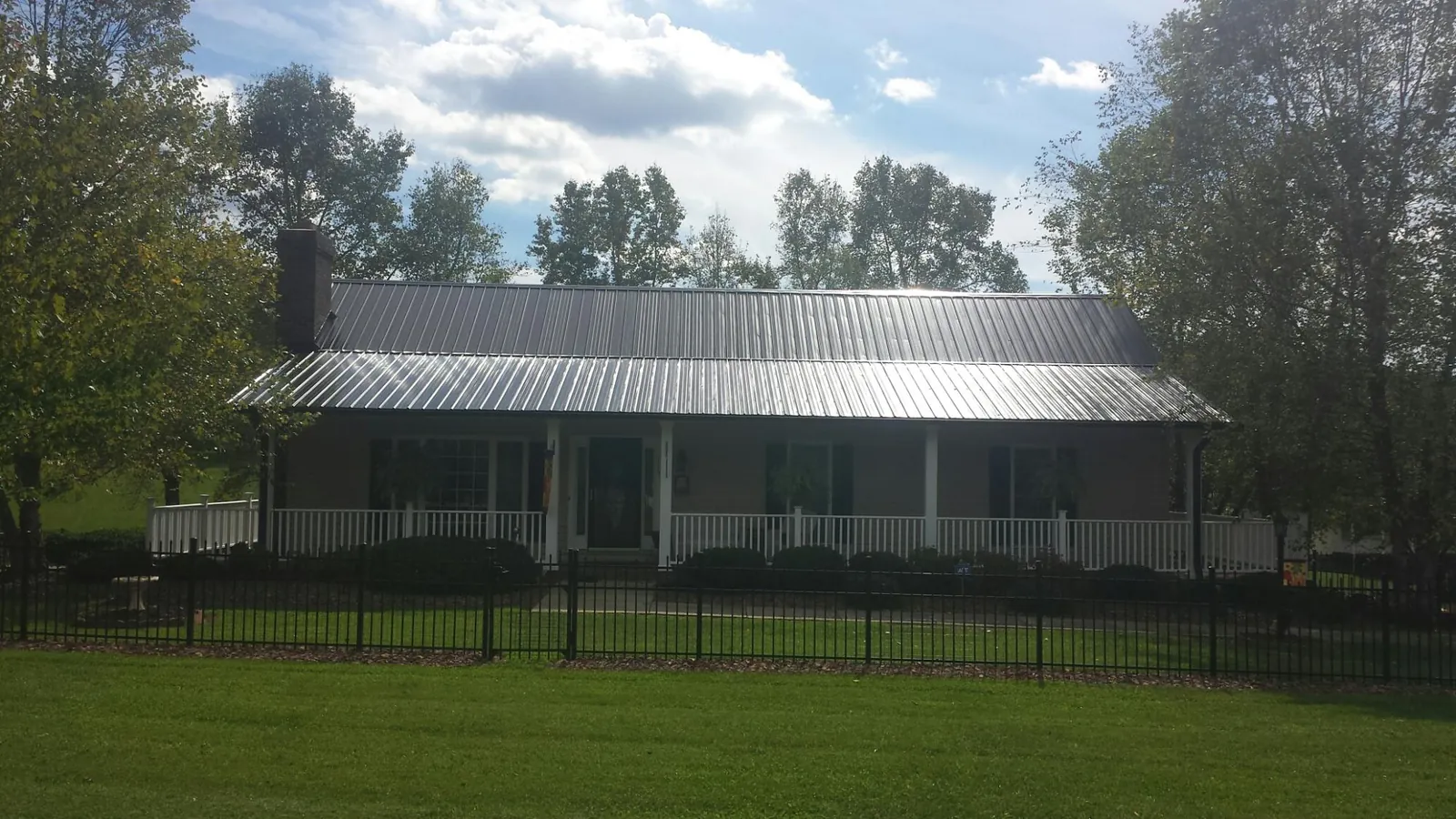 Gray metal roof on a brick ranch with a full width front porch — Gutter Guard Installation work by our crew in Brasstown