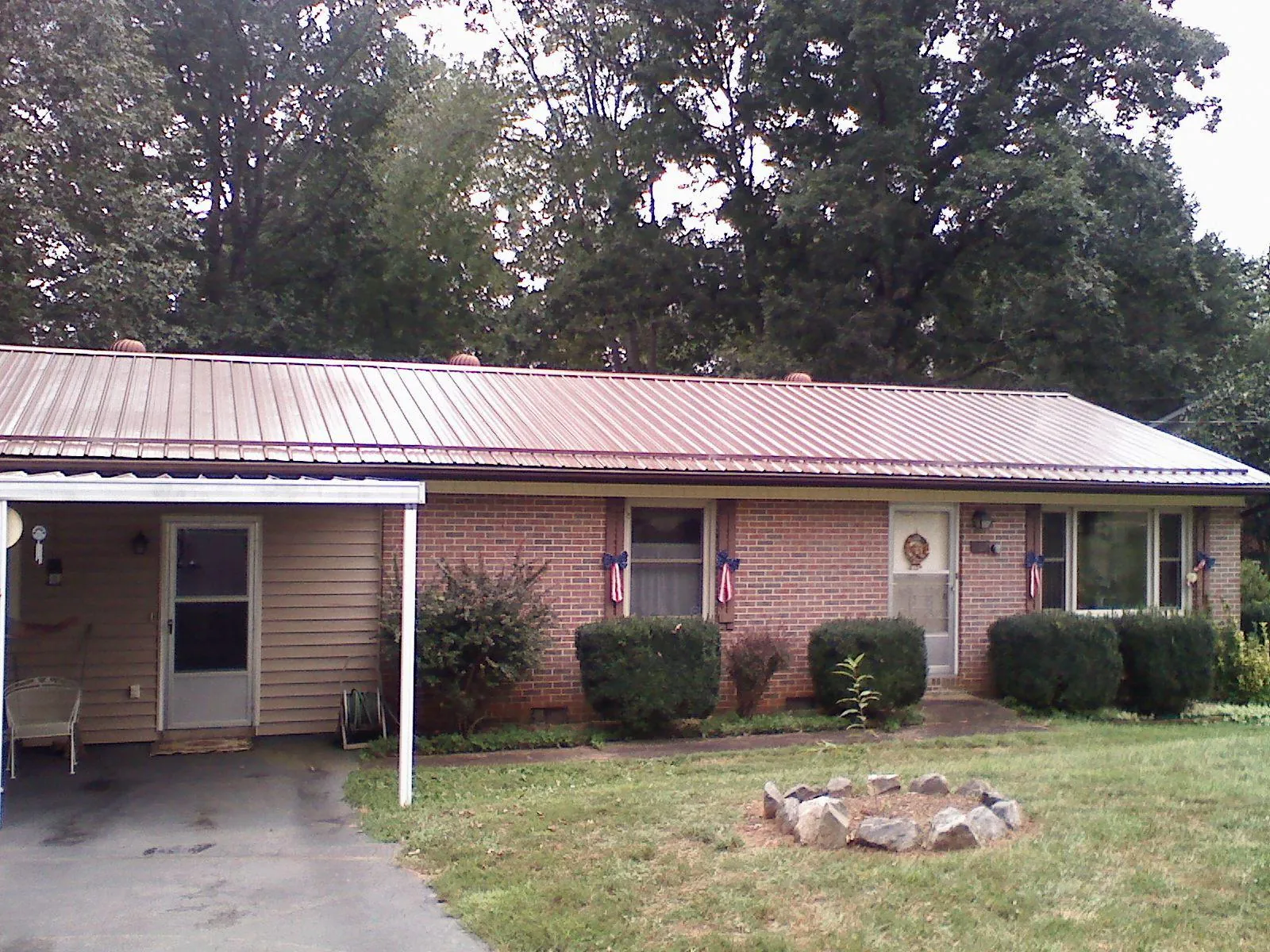 Bronze metal roof and carport on a brick ranch home — Roof Repair work by our crew in Brasstown