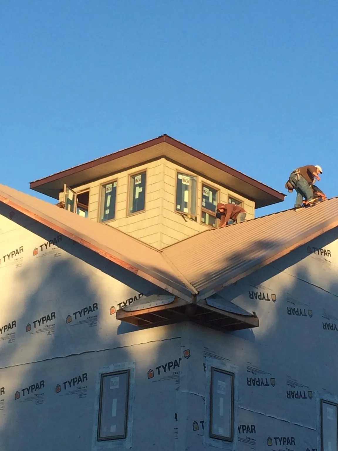Roofers working around a rooftop cupola on a new metal roof at sunset — Roof Waterproofing in Brasstown by Roofing Brothers